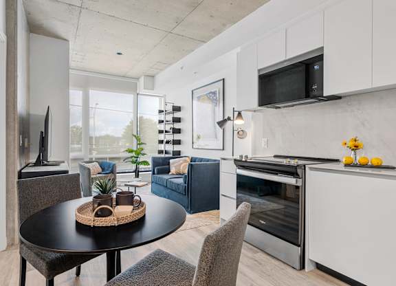 A modern kitchen with a black table and grey chairs.