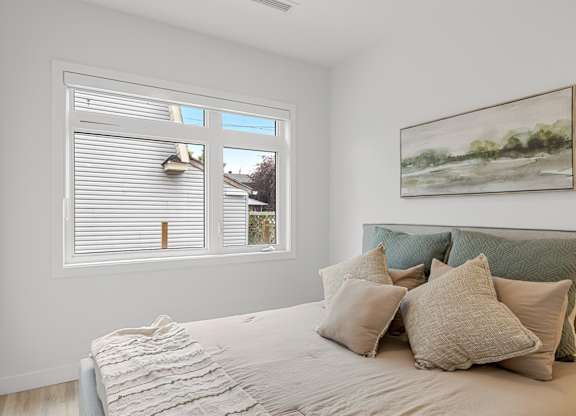 A bedroom with a bed, pillows, and a painting on the wall.