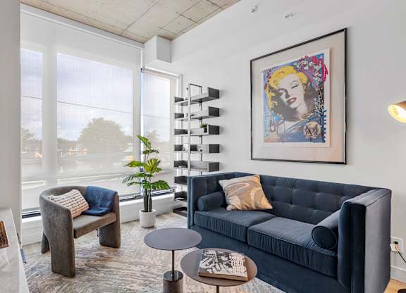A living room with a blue couch and a framed picture of a woman.