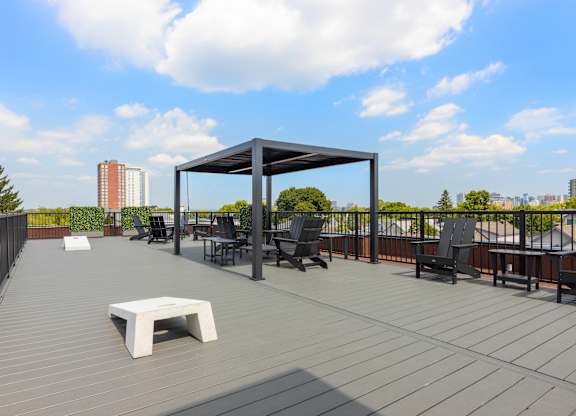 A wooden deck with a white table and chairs under a black canopy.
