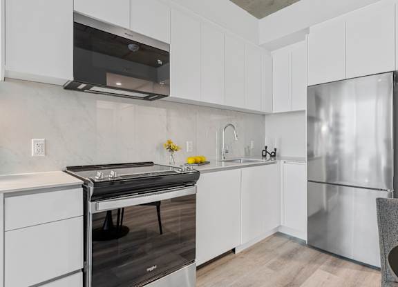 A modern kitchen with white cabinets and a stainless steel refrigerator.