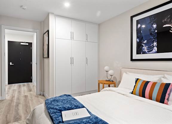 A bedroom with a bed, a nightstand, and a painting on the wall.