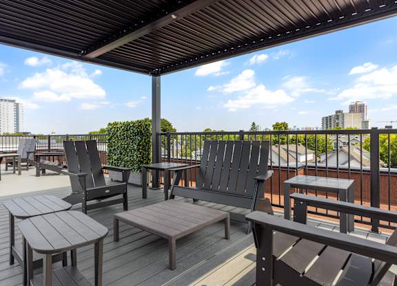 A wooden deck with chairs and tables overlooking a cityscape.