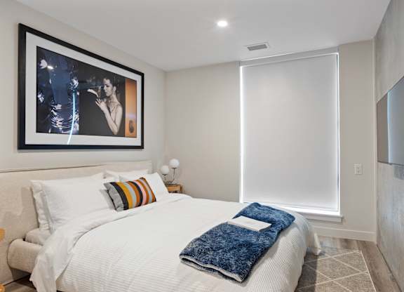 A bedroom with a large bed and a painting on the wall.