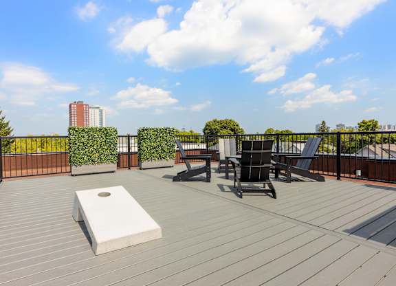 A wooden deck with a bench, chairs and a planter box.