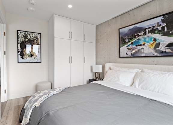 A bedroom with a large bed and a painting of a pool scene on the wall.