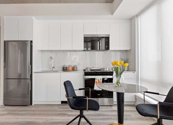 A modern kitchen with a glass table and black chairs.