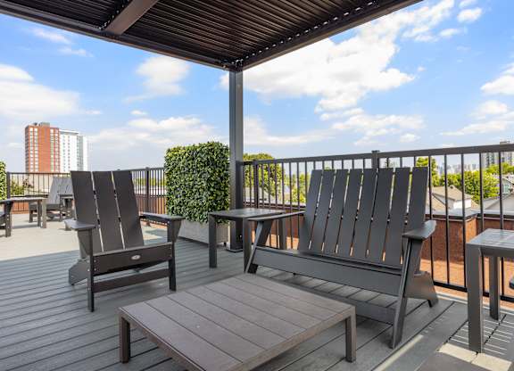 A wooden deck with a table, chairs and bench.