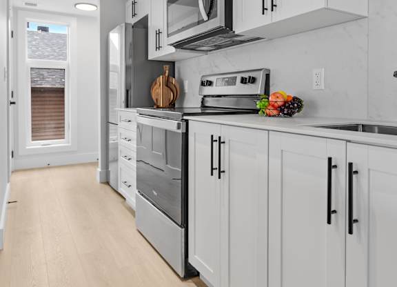 A modern kitchen with white cabinets and stainless steel appliances.