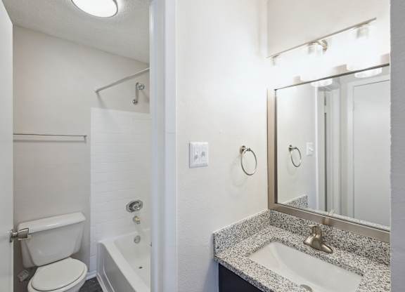 A bathroom with a toilet, sink, and mirror.