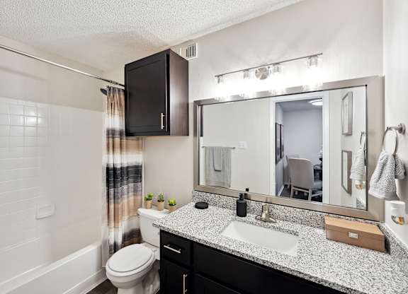 A bathroom with a white toilet, a sink, and a mirror.