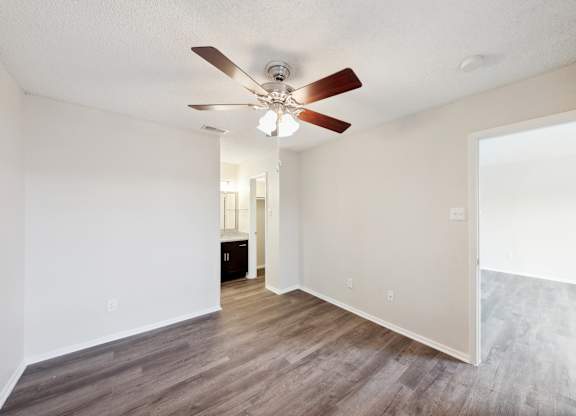 A room with a ceiling fan and wooden flooring.