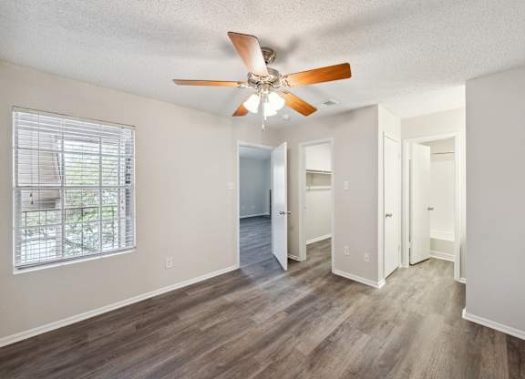 A room with a ceiling fan and wooden flooring.