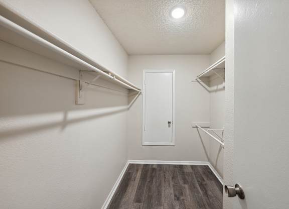A white door is in a hallway with wood floors and white walls.