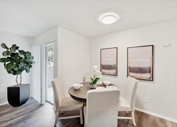 A dining room with a table set for two and two chairs.