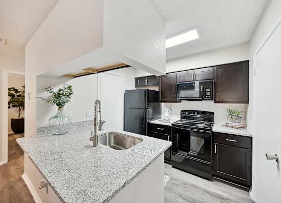 A kitchen with a granite countertop and black appliances.
