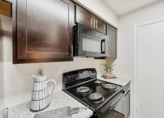 A modern kitchen with a black stove top oven and a black microwave above it.