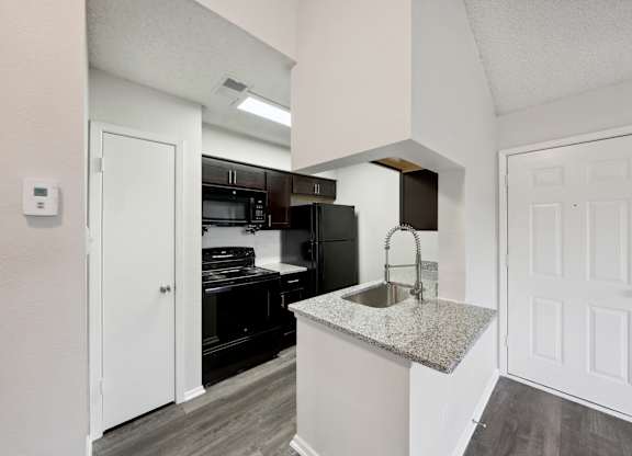 A kitchen with a granite countertop and white cabinets.