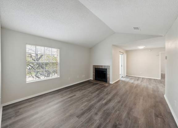A room with a fireplace and wood flooring.