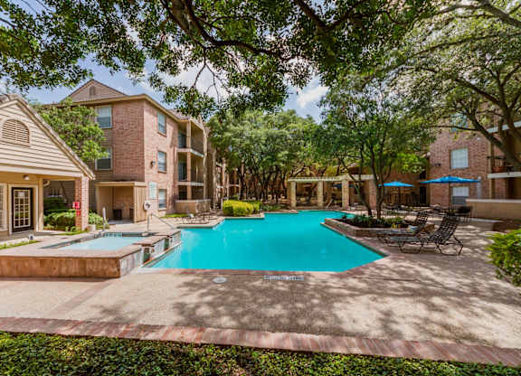 A swimming pool surrounded by trees and a building in the background.