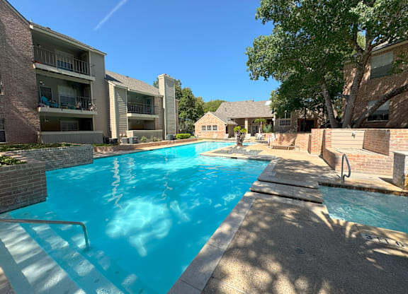 A swimming pool surrounded by apartment buildings on a sunny day.