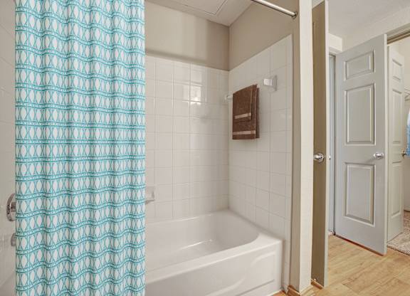A white bathtub with a blue shower curtain in a bathroom.