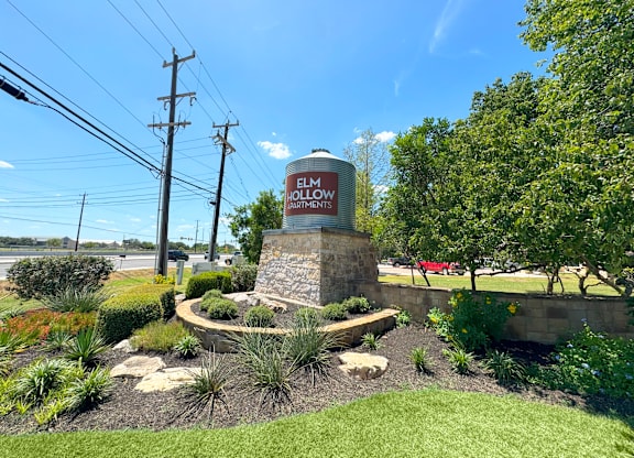 A sign for Elmwood Apartments stands in a landscaped area.
