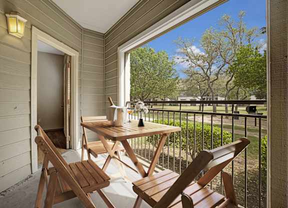 A wooden table and chairs are on a balcony.