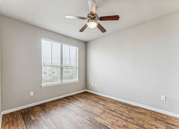 A room with a ceiling fan and wooden flooring.
