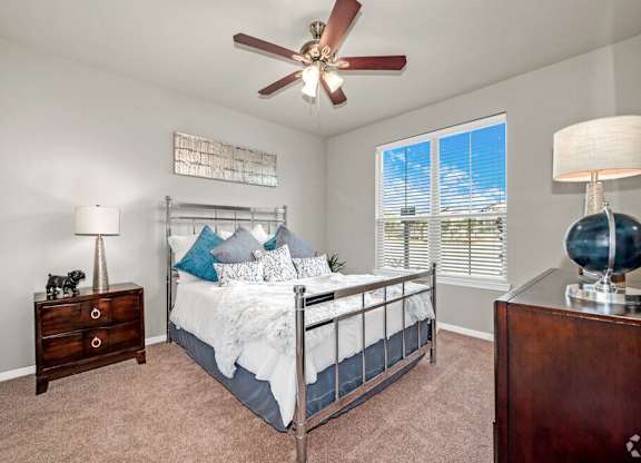 A bedroom with a bed, dresser, and ceiling fan.