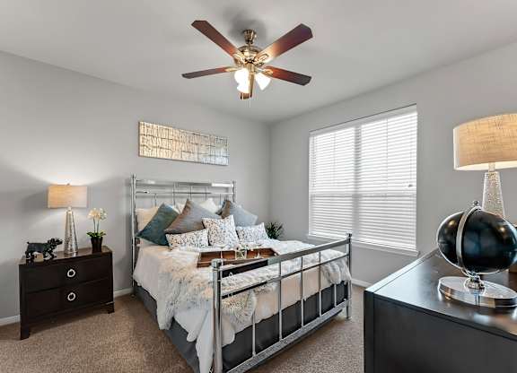 A bedroom with a bed, nightstand, and a ceiling fan.