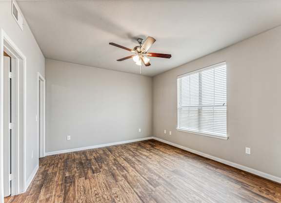 A room with a ceiling fan and wooden flooring.