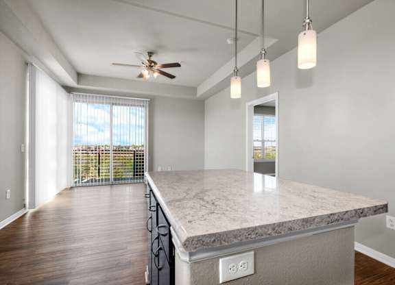 A spacious kitchen with a marble countertop and a ceiling fan.