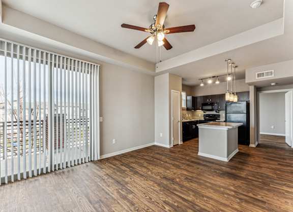 A spacious living room with a ceiling fan and sliding glass doors.