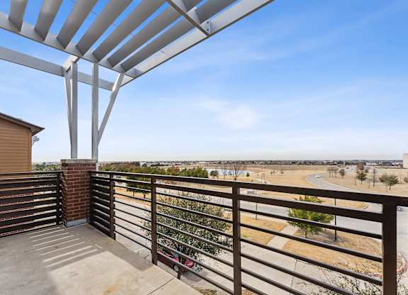 A balcony with a metal railing and a concrete floor.