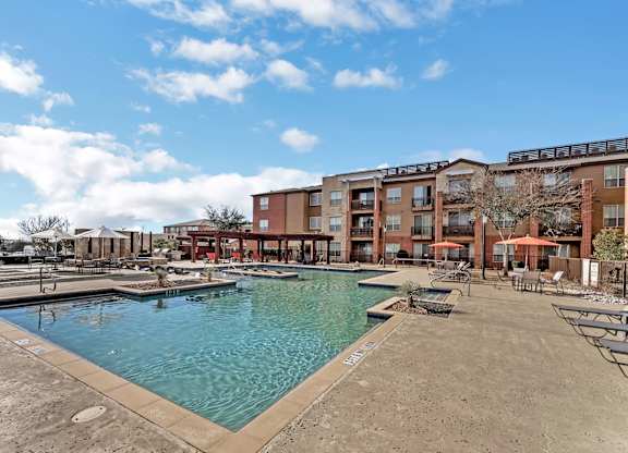 A large swimming pool in front of apartment buildings.