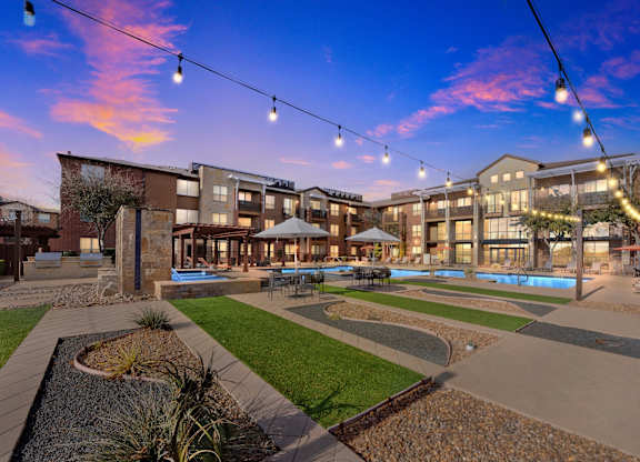 A sunset view of a courtyard with a pool and apartment buildings.