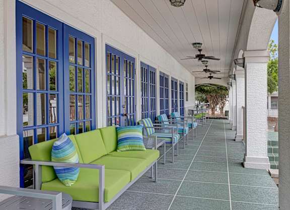 A long row of green couches are lined up on a patio.