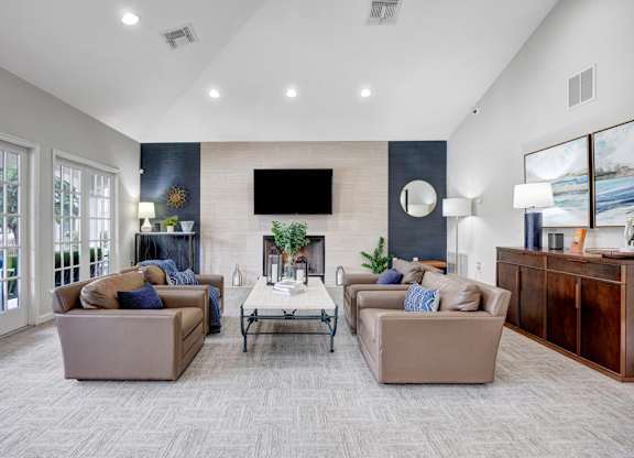 A living room with a grey carpet and a flat screen TV mounted on the wall.