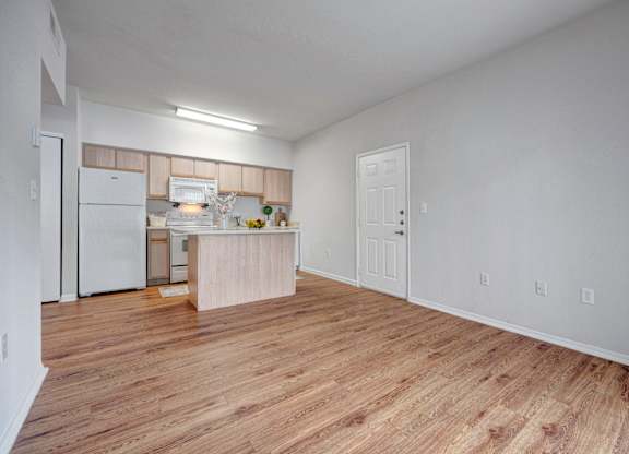 A kitchen with white appliances and wooden floors.