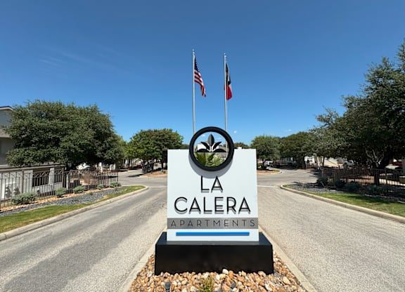 A sign for La Calera Apartments stands in front of a road.