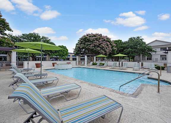 A pool with sun loungers and umbrellas.