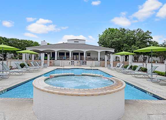 A large outdoor swimming pool with a hot tub in the middle of it.