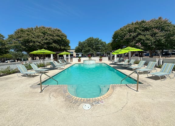 A large swimming pool surrounded by lounge chairs and umbrellas.