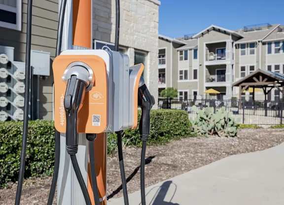 A row of electric vehicle charging stations are installed outside apartment buildings.