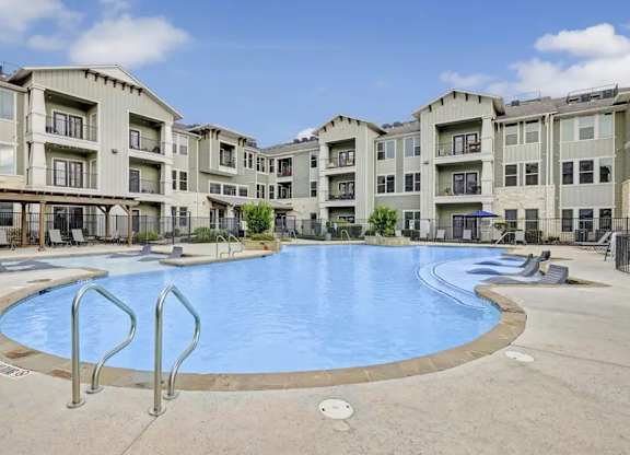 A large swimming pool in front of apartment buildings.