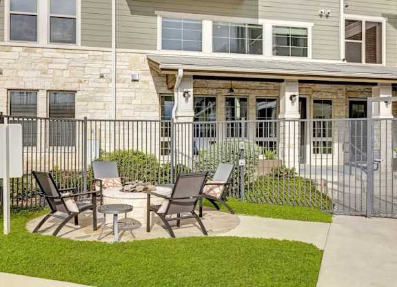 A patio with chairs and a table is in front of a house.
