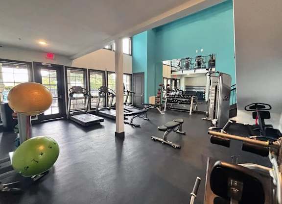 A gym with a variety of equipment including weights and exercise balls.