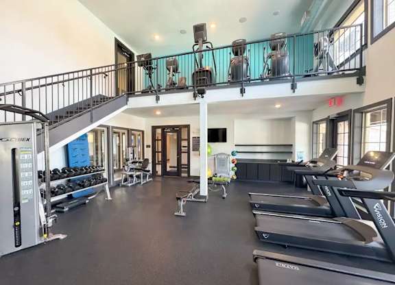 A gym with treadmills, weights, and a balcony.