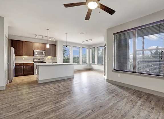 A spacious kitchen with wooden floors and a ceiling fan.